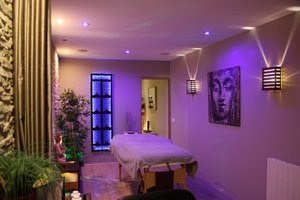 Table de massage dans une salle d'ambiance violette avec plantes et décoration zen